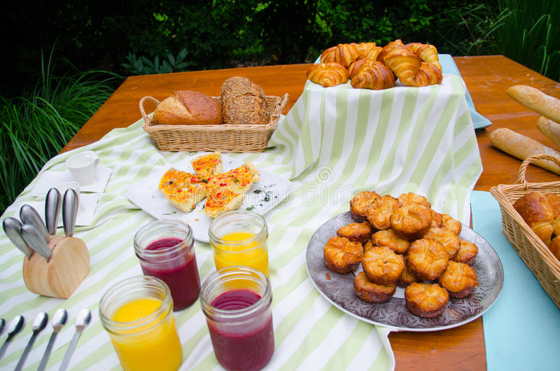 breakfast-picnic-buffet-bread-croissants-juice-pastries-quiche-garden-setting-43976872.jpg